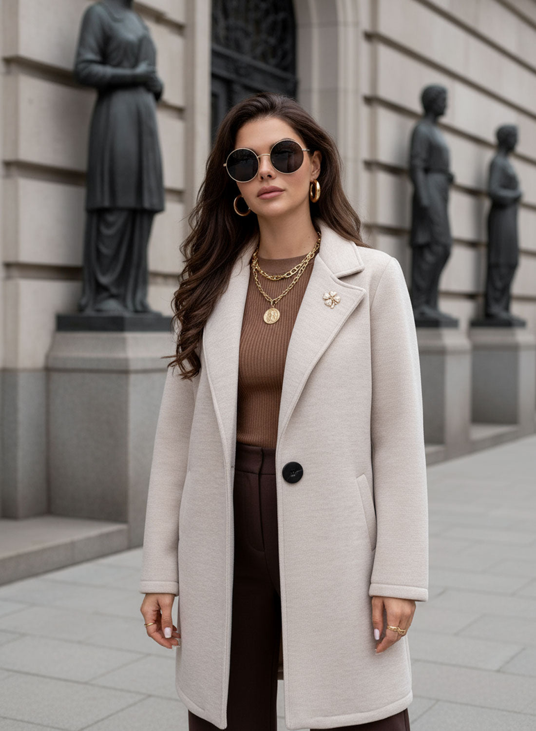Cappotto beige con bottone nero e spilla